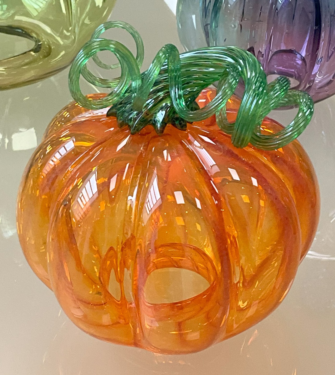Citrouille en verre soufflé à la main, nervurée, avec queue torsadée, déclinée en couleurs saisonnières ou audacieuses.